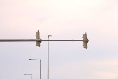 Low angle view of street lights and road signals against sky