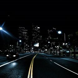 Road passing through illuminated city at night