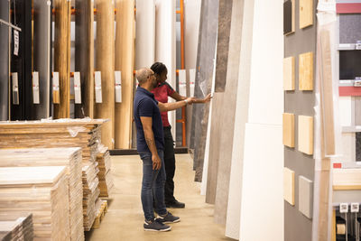 Side view of male customer with saleswoman choosing laminated boards at hardware store