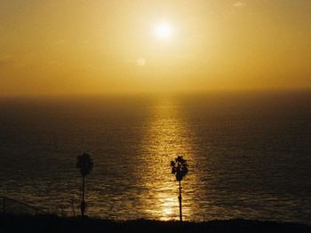 Silhouette woman walking on beach against sky during sunset