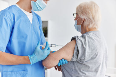 Midsection of doctor vaccinating patient at clinic