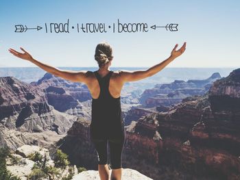 Rear view of man with arms outstretched against mountain