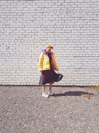 Full length of woman walking against brick wall