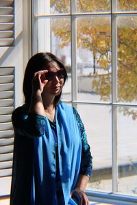 Woman standing by window at home 