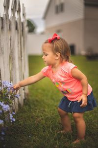 Baby girl touching flowers in yard