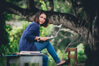 Young woman using phone while sitting on seat