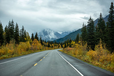 Road amidst trees and mountains against sky