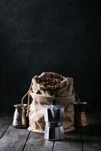 Roasted coffee beans in sack by espresso maker against wall