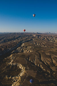 Hot air balloons flying over landscape against blue sky