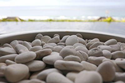 Close-up of pebbles in container against sea