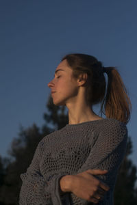 Beautiful young woman looking away against sky