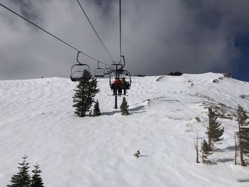 Ski lift over snow covered mountains against sky