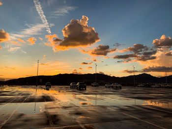 Cars on street against sky during sunset