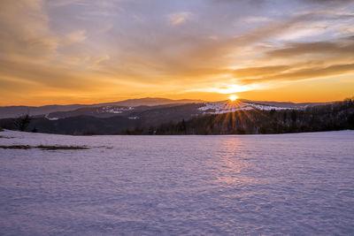 Scenic view of snowcapped mountains against sky during sunset