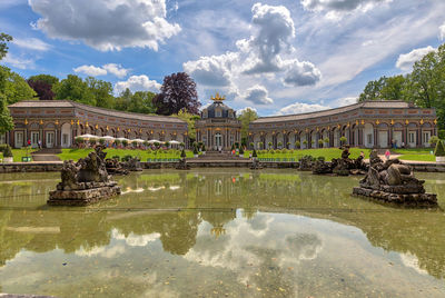 Reflection of building in pond against cloudy sky