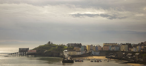 View of buildings in sea against cloudy sky