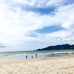 View of people on beach against cloudy sky