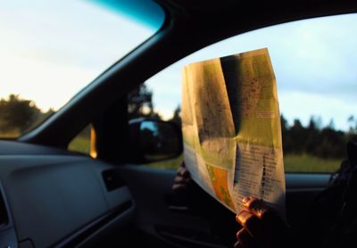 Cropped image of woman holding map while sitting in car