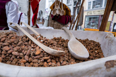 Close-up of roasted almonds in container for sale at market in historic town