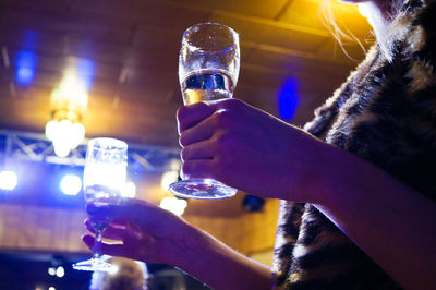 Midsection of woman holding drinks at nightclub