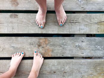 Low section of women with barefoot standing on wooden plank