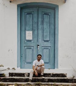 Portrait of young man sitting at entrance of building