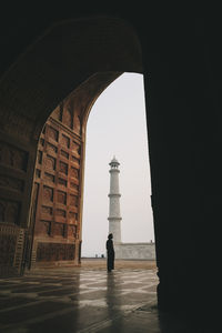 Young woman looking at taj mahal from inside kau ban mosque during sunrise, agra, india