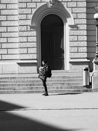 Side view of man standing on street by building during sunny day