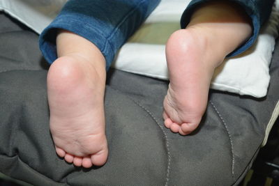 Low section of baby lying on bed