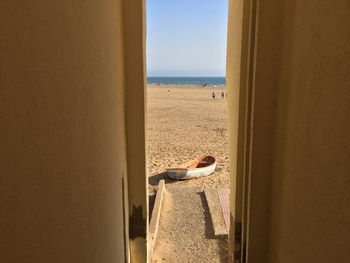 Rear view of man lying on beach against sky