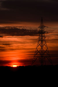 Low angle view of silhouette electricity pylon against sky during sunset