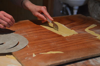 Person cutting flat bread on wooden board