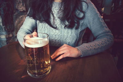 Midsection of man drinking glass on table