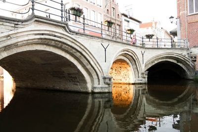 Arch bridge in city against sky