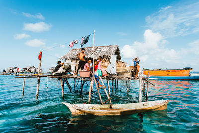 People on boat in sea against sky