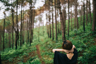 Rear view of woman stretching in forest