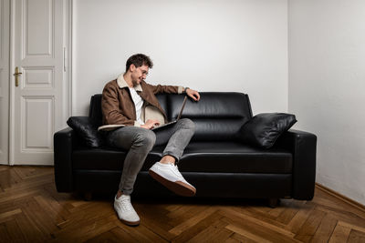 Young man using laptop while sitting on sofa at home