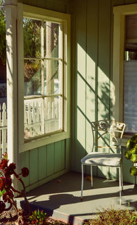 Sunny window of patio porch with vintage metal chair in sunlight and shadows