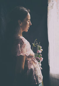 Woman with bouquet of flowers near a window iii