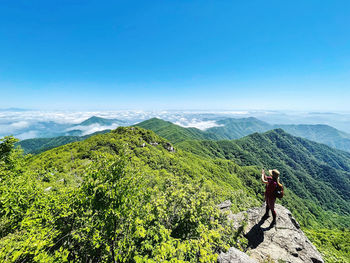 Woman standing on mountain against blue sky