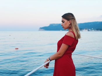 Young woman standing in sea against sky