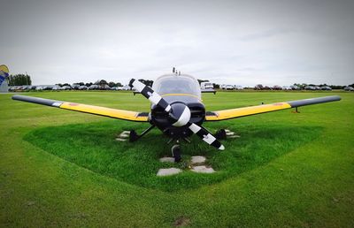 Airplane flying over field against sky