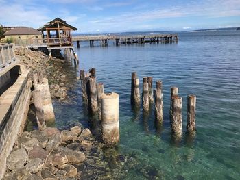 Wooden posts in sea against sky