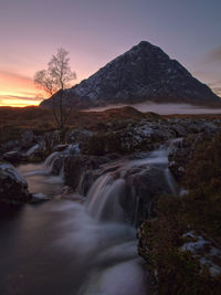 Scenic view of river stream against sky at sunset