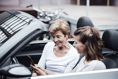 Side view of woman using mobile phone while sitting in car