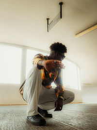 Young man crouching at home