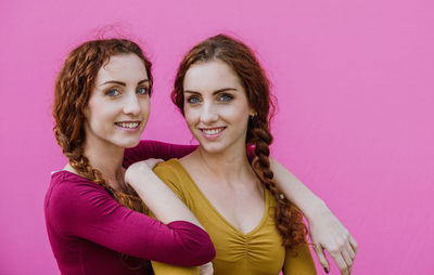 Portrait of smiling siblings against pink background