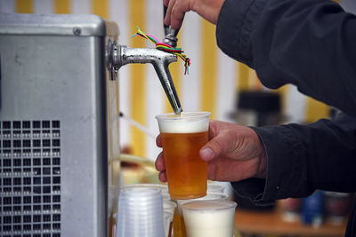 Cropped hands of man filling beer in glass