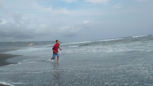 Rear view of man on beach against sky