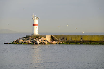 Lighthouse by sea against sky